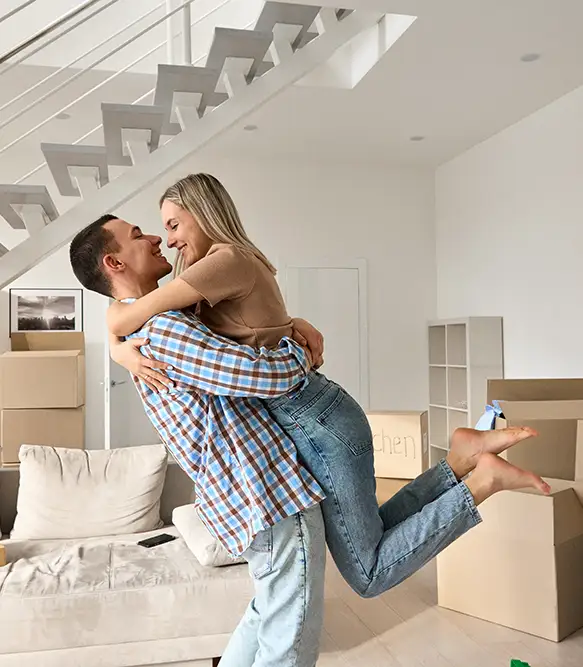 Photo of happy young couple hugging with moving boxes around them.