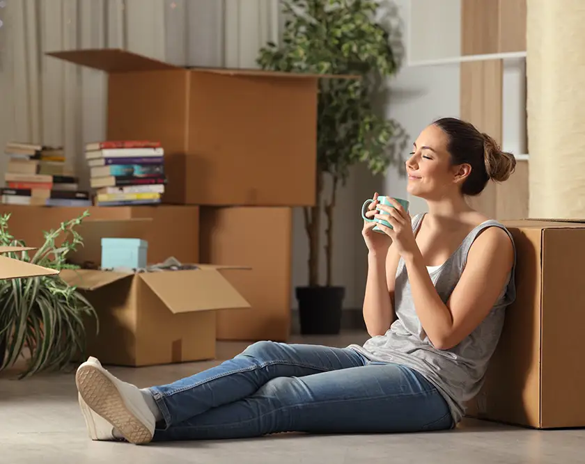 Photo of woman with a hot drink and moving boxes.